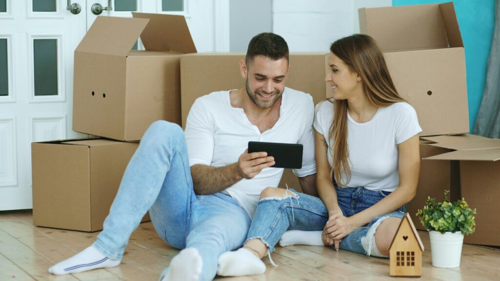 Couple looking at a tablet surrounded by moving boxes