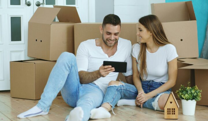 Couple looking at a tablet surrounded by moving boxes