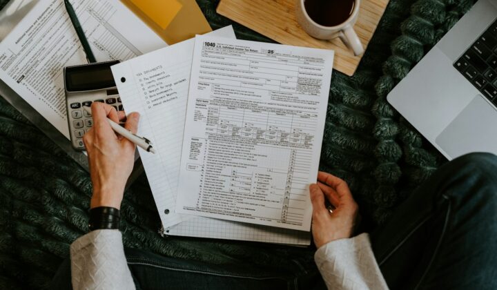 Person reviewing documents with a calculator and laptop