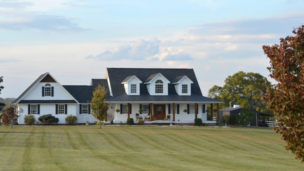 White farmhouse with a wraparound porch in the countryside